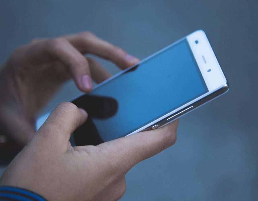 手机屏幕显示日韩系列一线二线三线 App 的品牌档案页，四项基础信息以卡片形式排列，右侧有一列可勾选的自查清单，背景是浅色木质桌面与一支笔